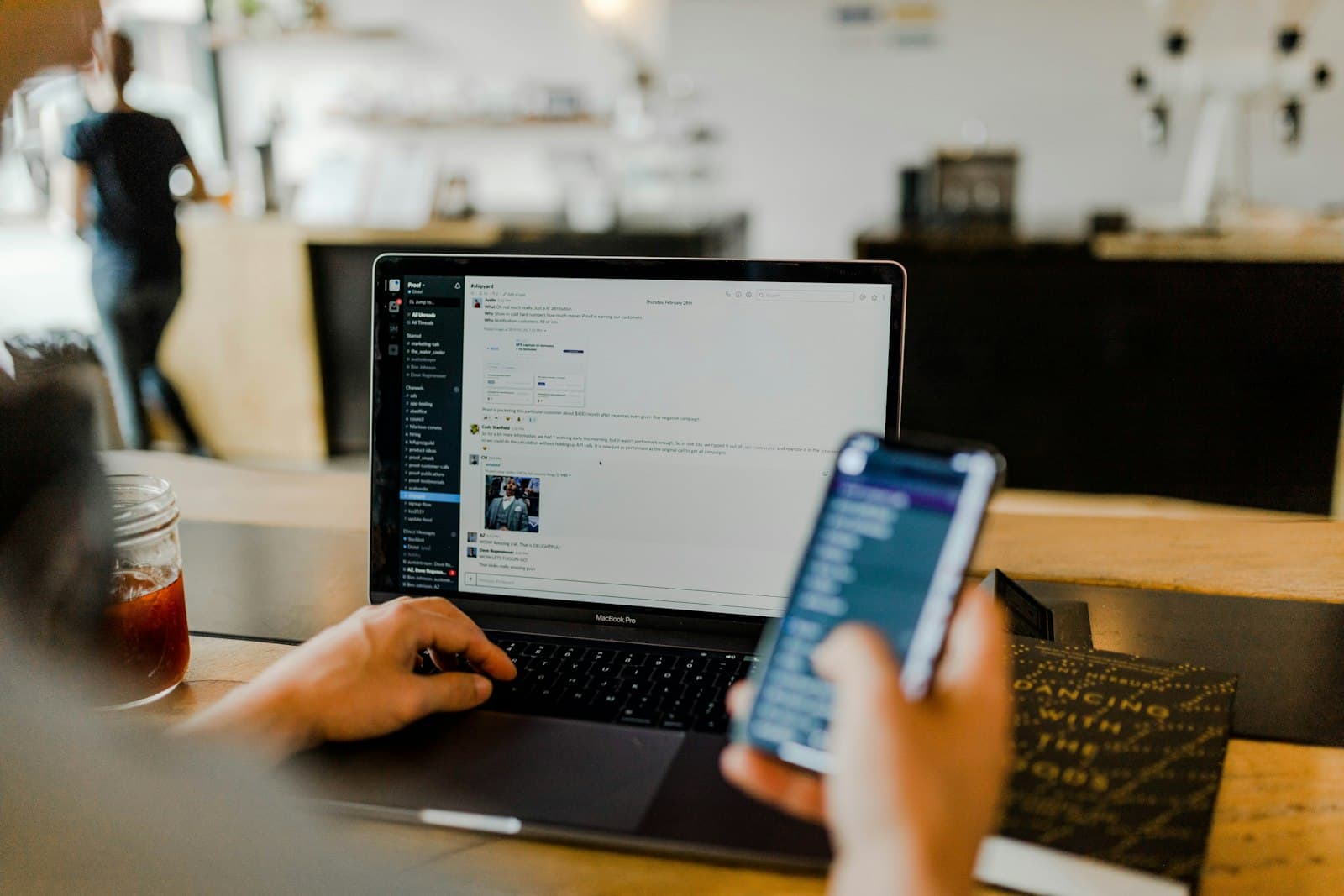 Person using a laptop and smartphone at a café table