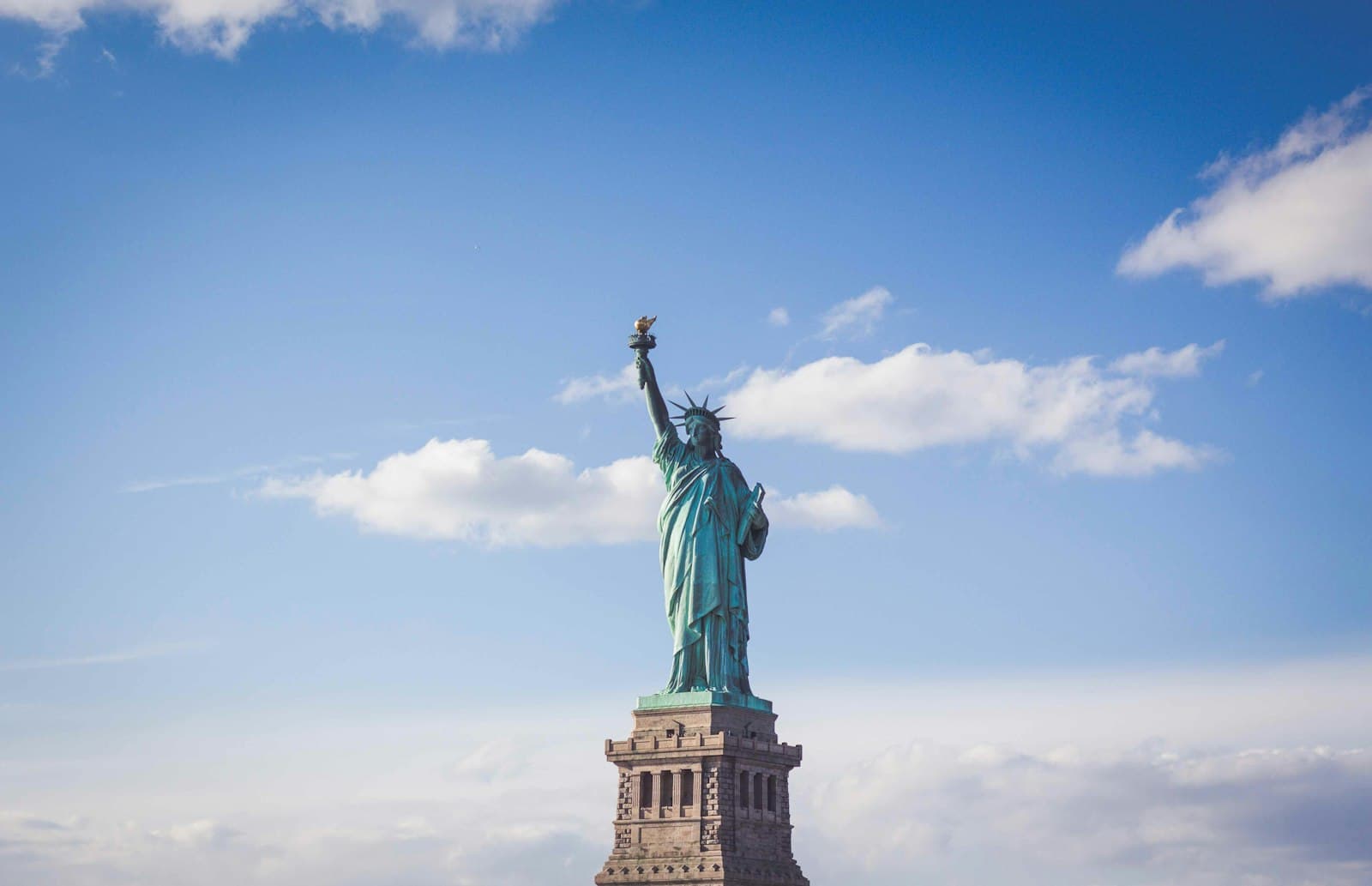 The Statue of Liberty against a blue sky with scattered clouds