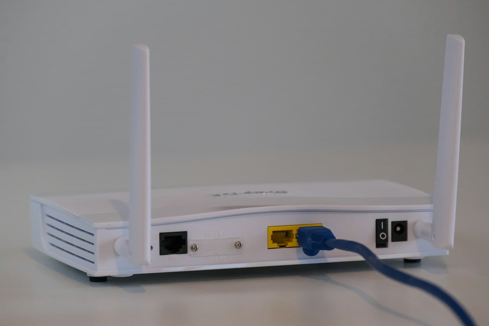 White wireless router with antennas and a network cable connected